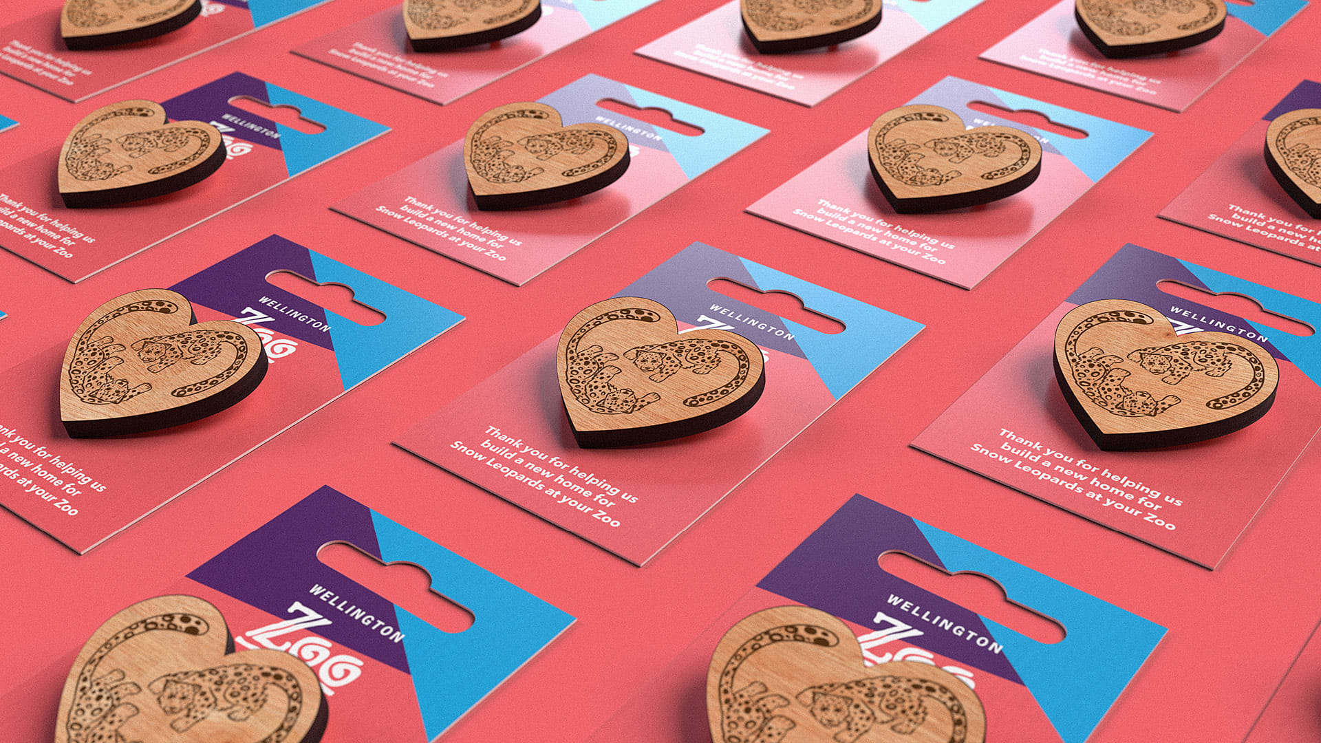 The snow leopard pins for Wellington Zoo, displayed on a coral pink and blue background, designed by Bradley Pratt